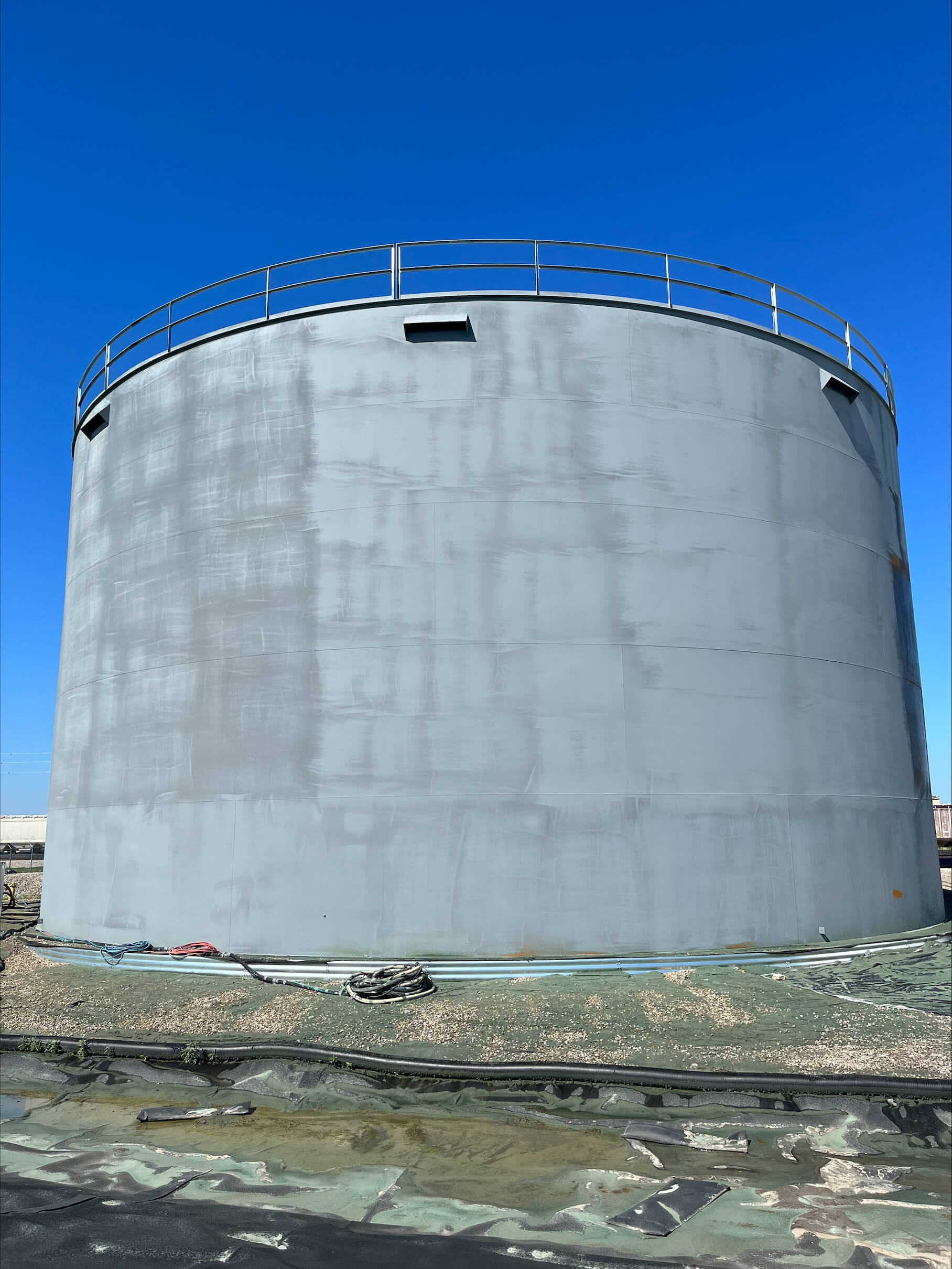 A newly constructed steel ethanol storage tank is seen following surface preparation via abrasive blasting.