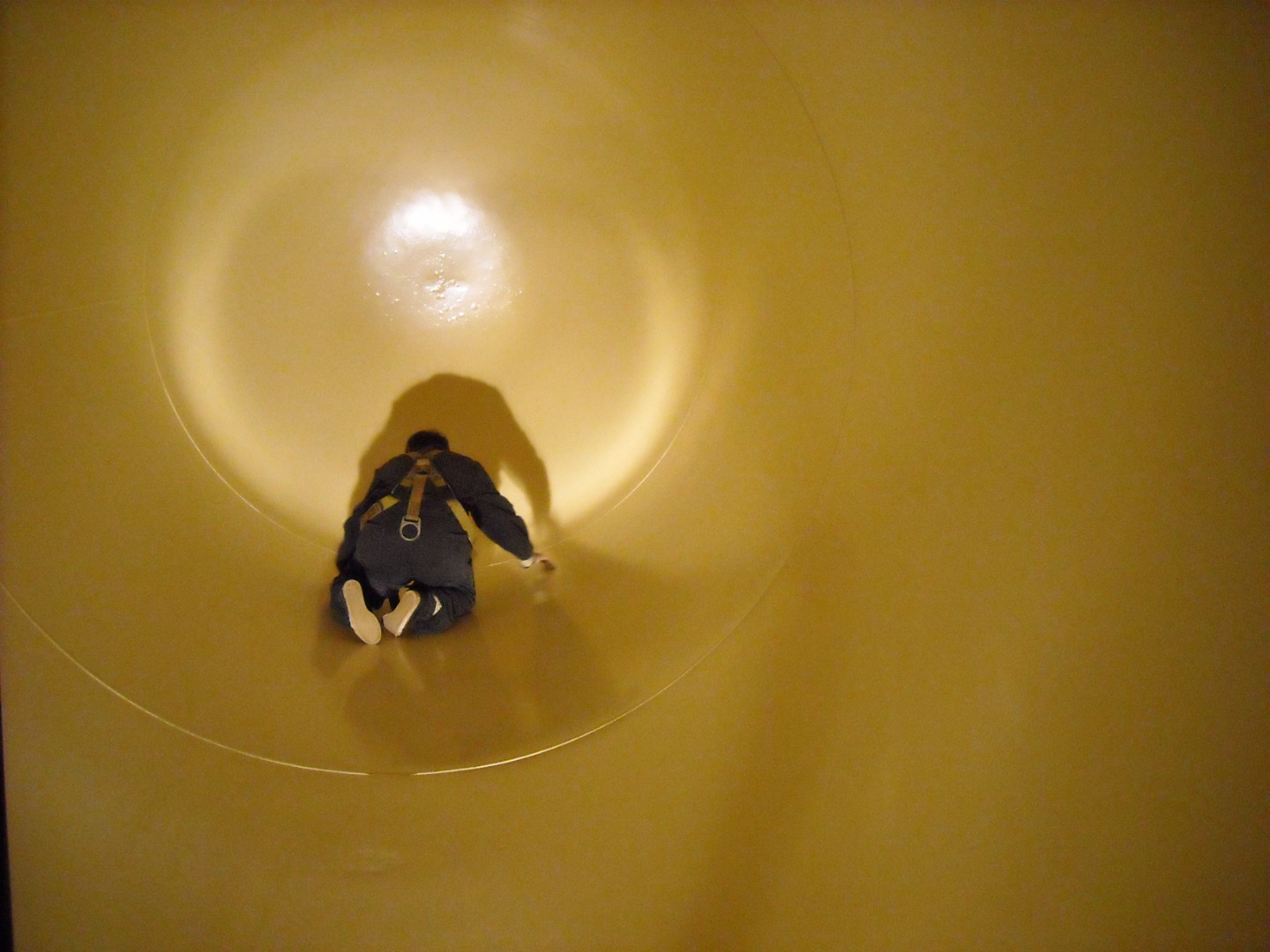A person kneeling inside a rail tank car while inspecting the interior floor.